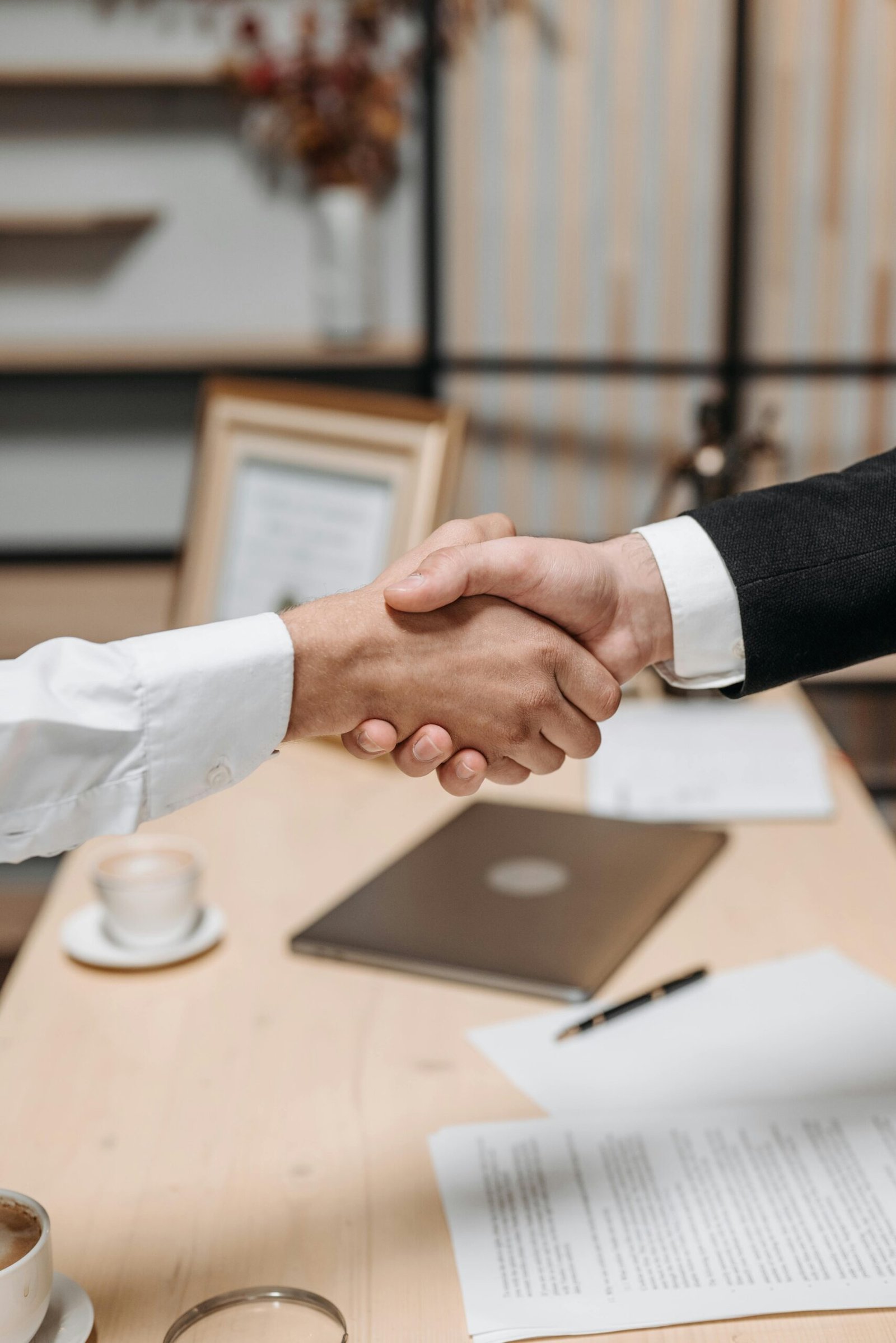 What You Need to Know Before You Start Your LLC Close-up of two people shaking hands in an office, symbolizing agreement and partnership.